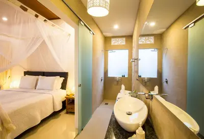 a bedroom with a bed and a sink and a tub at Villa Kamboja Deluxe in Seminyak