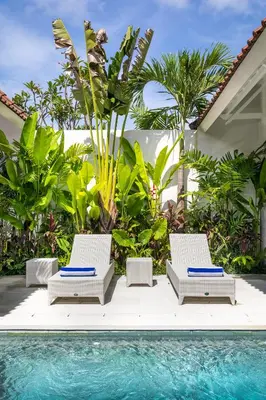 two lounge chairs next to a swimming pool at Villa Wahah in Seminyak