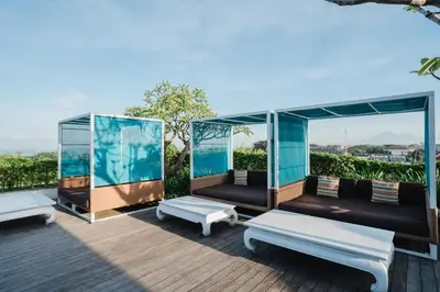 a deck with two benches and a table at Rama Residence Padma in Legian