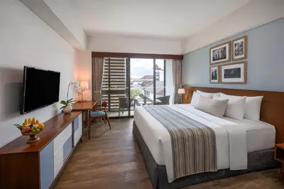 a bedroom with a bed and a desk and a television at Rama Residence Padma in Legian