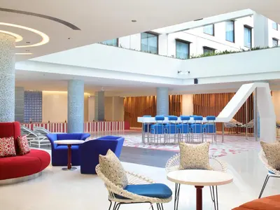 a lobby with blue and red chairs and tables at Holiday Inn Express Baruna by IHG in Kuta