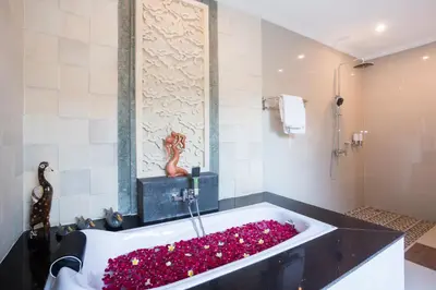 a bathroom with a bath tub filled with flowers at Kubu Petitenget Suite Seminyak in Seminyak