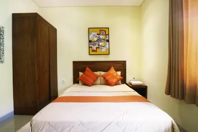 a bedroom with a large bed with orange pillows at Dee Mansion Bali in Denpasar