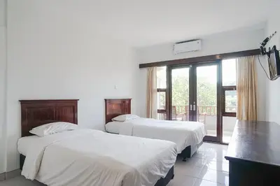 two beds in a room with a window at Indopurejoy House - Komala Indah Cottages in Kuta