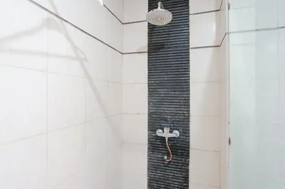 a shower with a black hose in a bathroom at Indopurejoy House - Komala Indah Cottages in Kuta