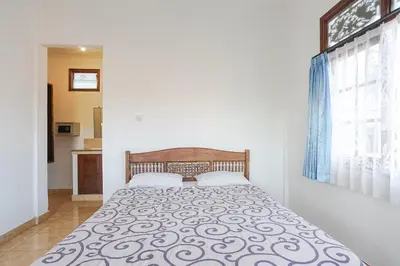 a bedroom with a bed with a black and white blanket at Indopurejoy House - Komala Indah Cottages in Kuta