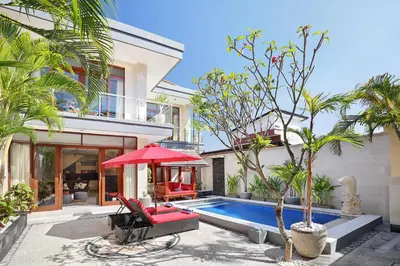 a villa with a swimming pool and a red umbrella at Villa Nova in Legian