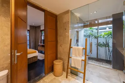 a bathroom with a shower and a toilet and a bedroom at Villa Dee 6 in Seminyak