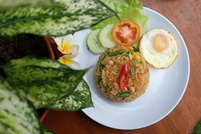 a plate of food with rice and vegetables on a table at D'Pande Kuta in Kuta