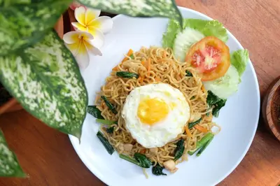 a plate of noodles with an egg on top at D'Pande Kuta in Kuta