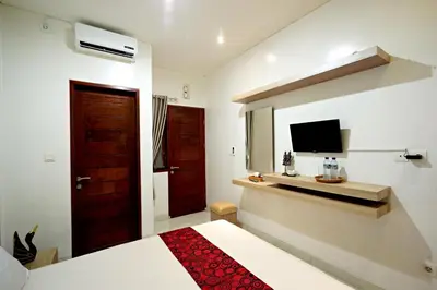 a hotel room with a bed and a television at D'Pande Kuta in Kuta