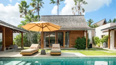 an umbrella and chairs next to a swimming pool at Villa Du Ho by Villa Finder in Kerobokan