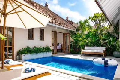 a villa with a swimming pool in front of a house at Villa Tsuchi in Seminyak
