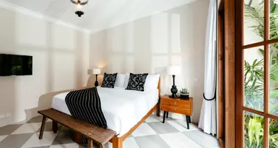 a white bedroom with a bed and a window at Villa Tsuchi in Seminyak