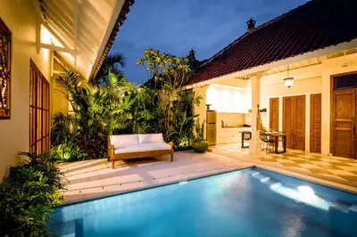 a villa with a swimming pool and a chair at Villa Tsuchi in Seminyak