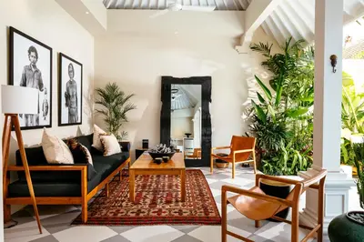 a living room with a black couch and a mirror at Villa Tsuchi in Seminyak