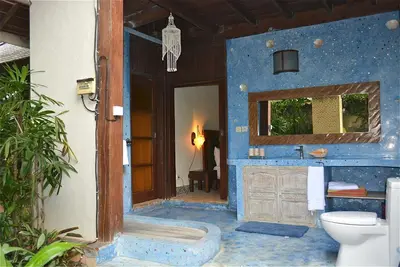a blue bathroom with a toilet and a mirror at Villa Una in Seminyak