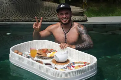a man in the water with a tray of food at Ambermoon Villas in Seminyak