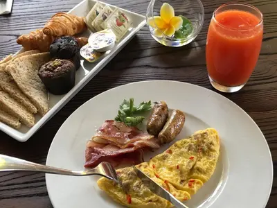 a table with a plate of breakfast food and a drink at Anshel Hotel Seminyak in Seminyak