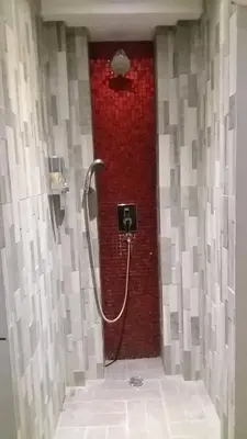 a shower in a bathroom with a red wall at Anshel Hotel Seminyak in Seminyak