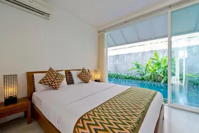 a bedroom with a bed and a large window at White Villa in Seminyak