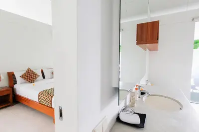 a bedroom with a bed and a sink and a mirror at White Villa in Seminyak