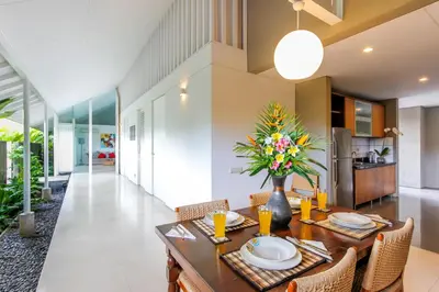 a dining room with a table with a vase of flowers at White Villa in Seminyak