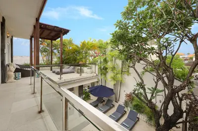 a balcony of a house with chairs and an umbrella at Villa Alba in Seminyak