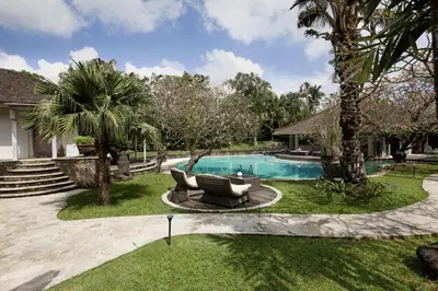 a backyard with a swimming pool and palm trees at Maya Villa - Seminyak in Seminyak