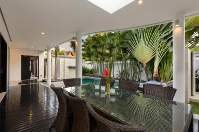 an indoor dining room with a glass table and chairs at Villa Maharani in Seminyak