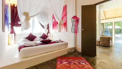 a bedroom with a bed with red and white curtains at Luxury Villa Kudeta 300m BEACH and heart of Seminyak in Seminyak