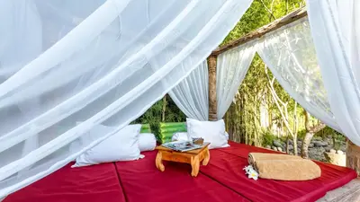a bedroom with a red bed with white drapes at Luxury Villa Kudeta 300m BEACH and heart of Seminyak in Seminyak