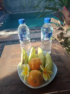 a plate of fruit on a table with two bottles of water at D'puja Home Stay and Spa in Nusa Dua