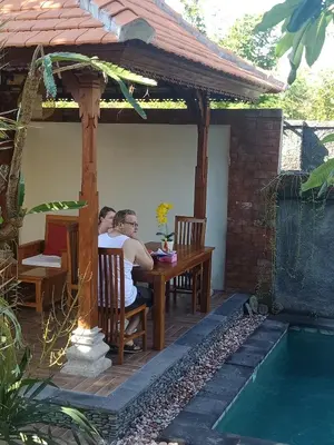 two men sitting at a table under a gazebo at D'puja Home Stay and Spa in Nusa Dua