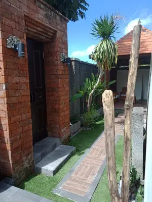 a brick house with a door and a wooden pole at D'puja Home Stay and Spa in Nusa Dua