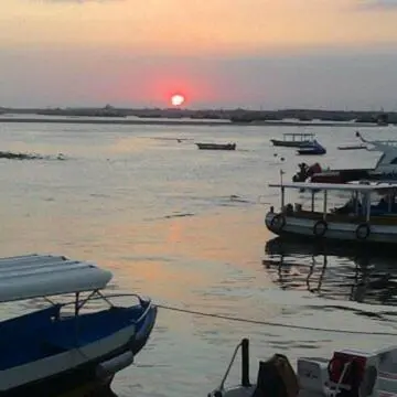 a group of boats in the water at sunset at D'puja Home Stay and Spa in Nusa Dua
