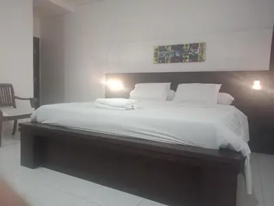 a bedroom with a large bed with white sheets at D'puja Home Stay and Spa in Nusa Dua