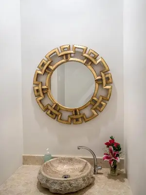 a bathroom sink with a gold mirror on the wall at Mahana Living in Denpasar