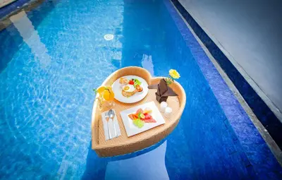 a floating island in a swimming pool with a tray of food at Apple Villa & Suite Seminyak in Seminyak