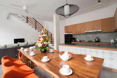 a dining room with a wooden table and orange chairs at Apple Villa & Suite Seminyak in Seminyak