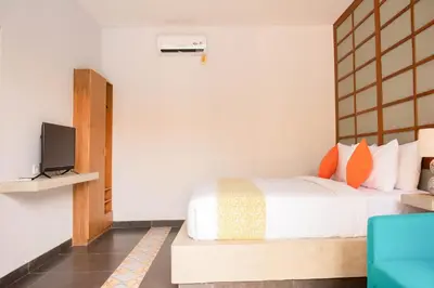 a bedroom with a bed and a tv on a wall at Apple Villa & Suite Seminyak in Seminyak