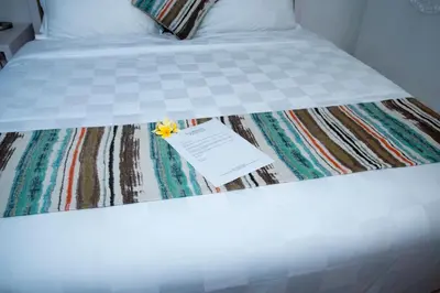 a white bed with a piece of paper on it at Sofi Apartment at Jayakarta Residence in Legian