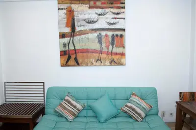a blue couch in a living room with a painting on the wall at Sofi Apartment at Jayakarta Residence in Legian