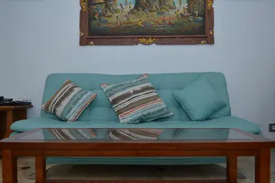 a blue couch with two pillows and a coffee table at Sofi Apartment at Jayakarta Residence in Legian