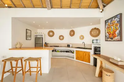 an open kitchen with a counter and stools at Villa Dipta in Seminyak