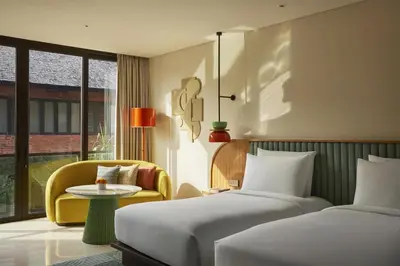 a hotel room with two beds and a chair at Kleo Seminyak, part of JdV by Hyatt in Seminyak