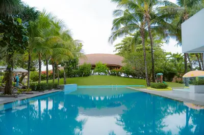 a pool at the resort with palm trees at Tijili Hotel Benoa in Nusa Dua