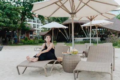 a woman in a black dress sitting on a chair at Tijili Hotel Benoa in Nusa Dua