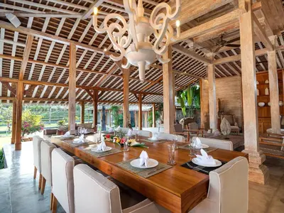 a dining room with a long wooden table and chairs at Mannao Estate by Villa Finder in Kerobokan