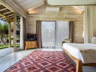 a bedroom with a bed and a flat screen tv at Mannao Estate by Villa Finder in Kerobokan